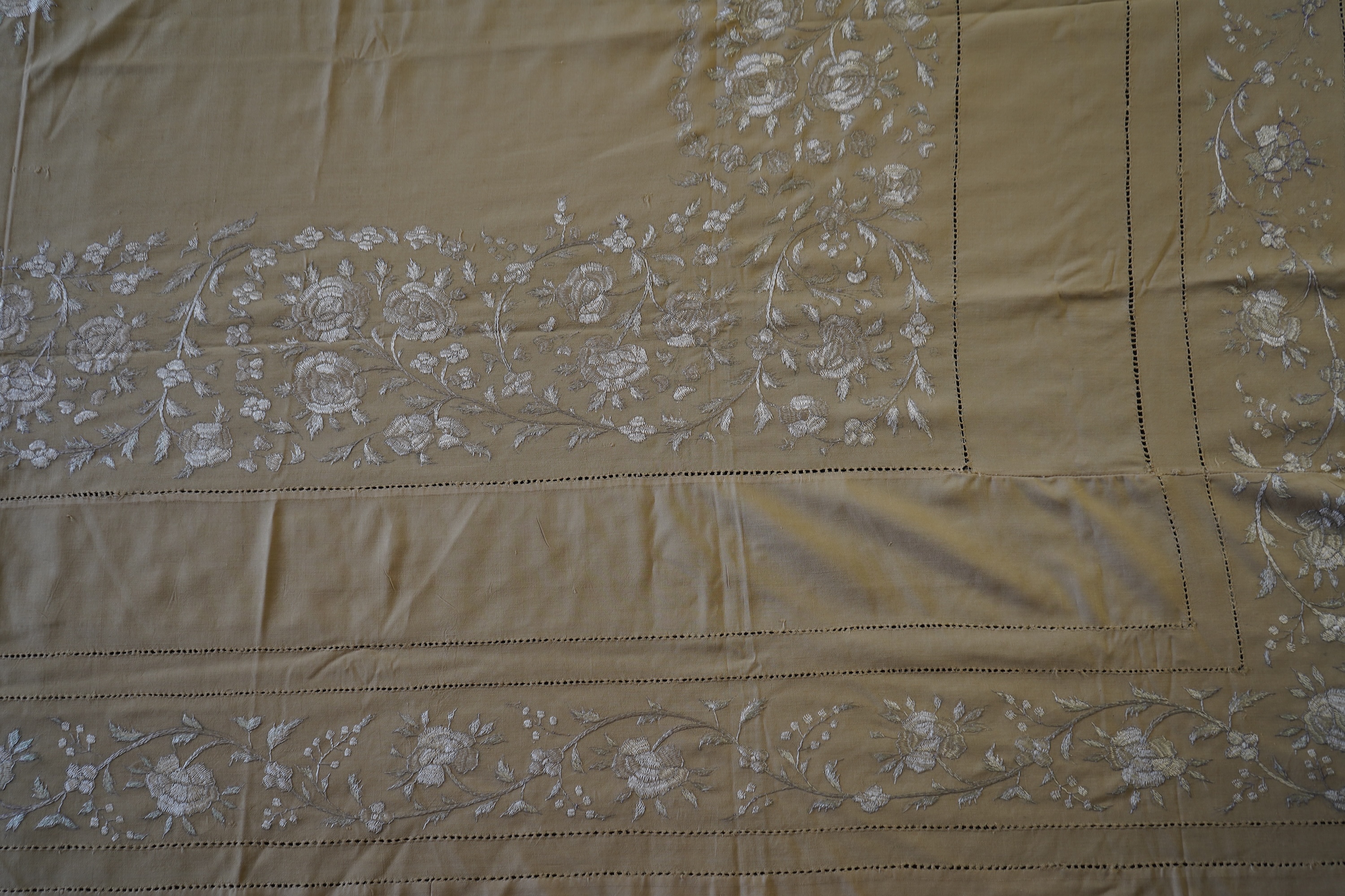 A 1920’s heavy shantung silk hand embroidered table cover. Worked with decorative rows of button hole stitch. Embroidered with white, green and blue silk flowers. 240cm x 204cm. Condition - some fine holes near corners,